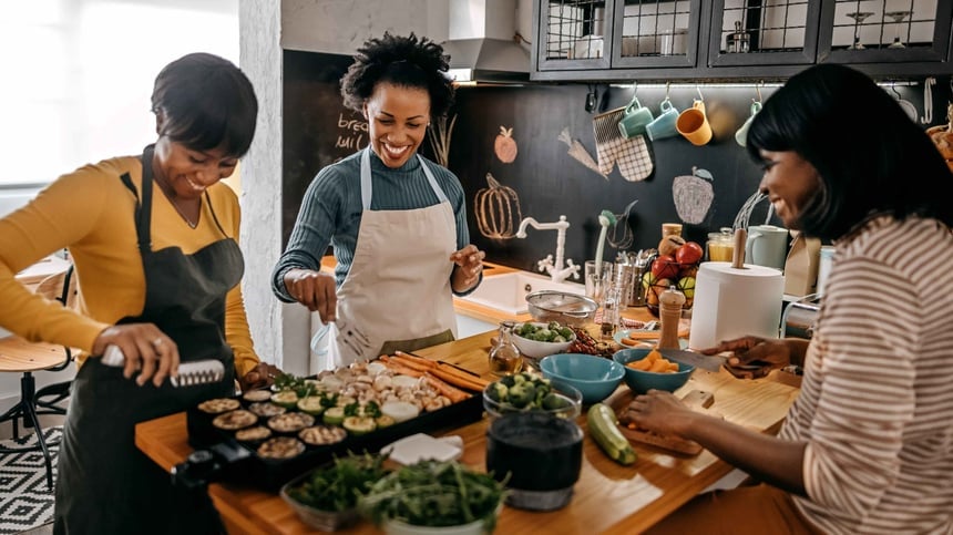 Three women cooking around a kitchen counter