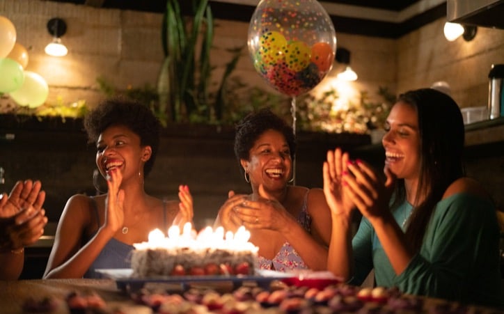 Women sitting around a cake celebrating a birthday 