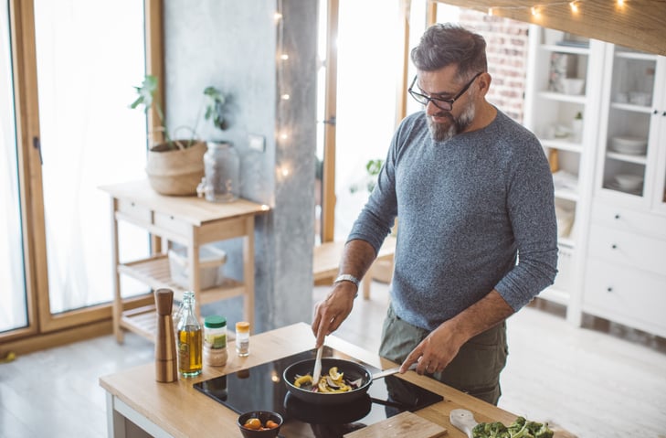 Older man cooking at a stovetop