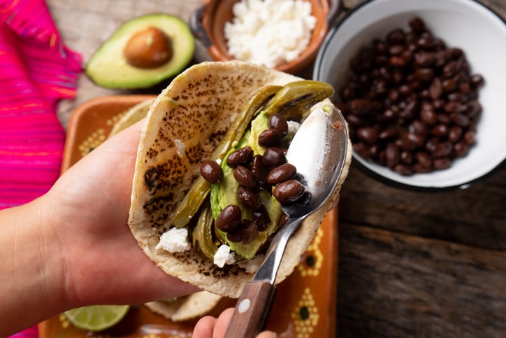 Someone holding a taco filled with black beans and avocado