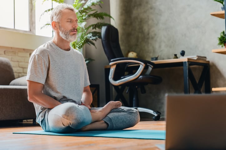 Man with gray hair meditating on the floor 