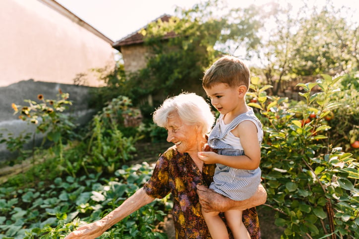 Grandma holding a toddler boy in her vegetable garden