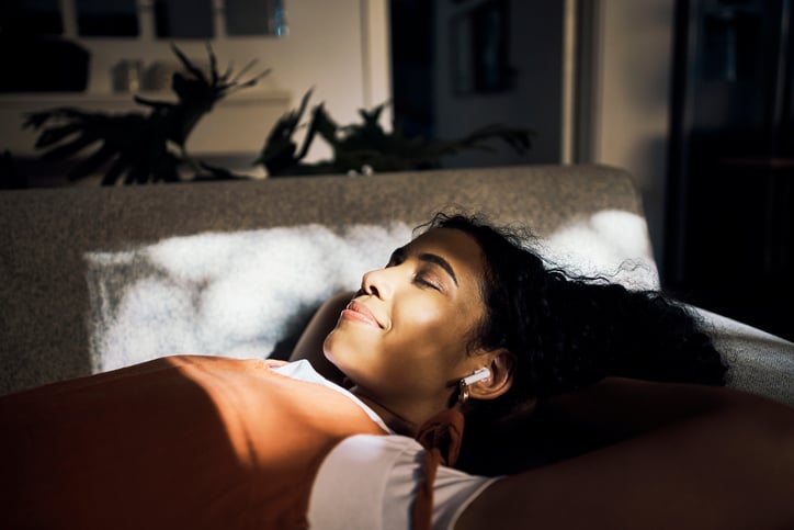 Woman laying on couch listening to music