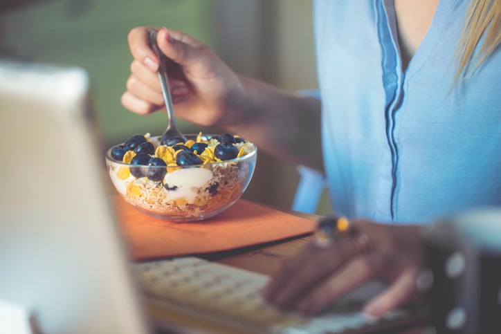 Woman eating cereal at a computer