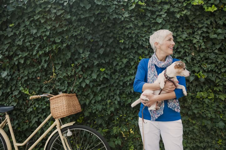 woman holding a small dog next to a bike